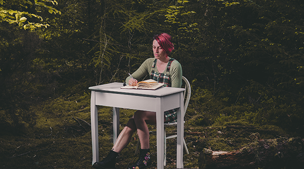 Press Review - Kim sitting at a desk in a woodland clearing